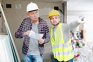 Architect discussing workflow with builder at construction site indoors