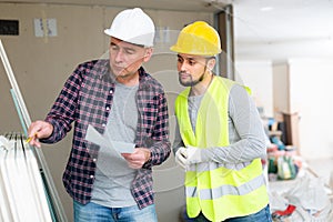 Architect discussing workflow with builder at construction site indoors