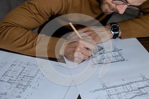 Architect drawing blueprint sketching design of house, making architectural construction building.