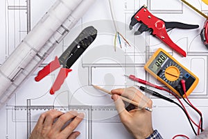 Architect Drawing Plan On Blueprint With Electrical Components