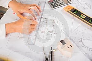 Architect drawing with ruler on house plan blueprint paper for repair tools on table