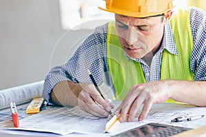Architect Engineer Builder, Building Designer working with floorplan at Construction Site