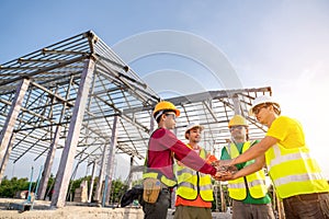 Architect and Engineer construction workers join hands while working at outdoors construction site. Building construction