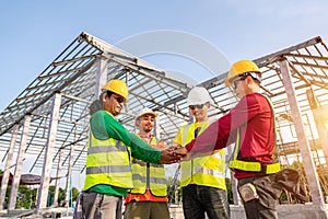 Architect and Engineer construction workers join hands while working at outdoors construction site. Teamwork Concept