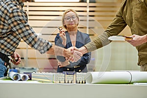 Architect and engineer construction workers shaking hands while working for teamwork in the office