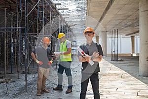 Architect, Engineer, Contractor, or Construction manager holding digital tablet standing with a group of worker at a construction