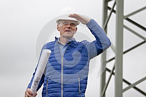 Architect or engineer with hard hat and blueprint in his hand looking out  for something