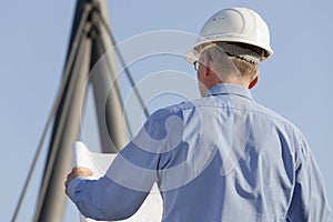Architect or engineer reading a construction plan in front of industrial background