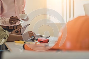 Architect or engineer reading message on phone during the meeting building plan design project in office. Construction engineering