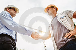 Architect engineer shaking hands other hand at construction site. Business teamwork, cooperation, success collaboratio