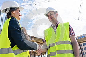 Architect and engineer or supervisor shaking hands on the construction site