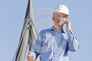 Architect or engineer talking on smart phone in front of technical construction