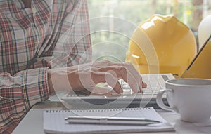 Architect engineer using laptop for working with helmet,