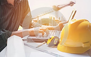 Architect engineer using laptop for working with yellow helmet,