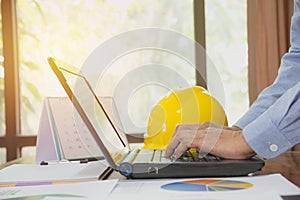 Architect engineer using laptop for working with yellow helmet o