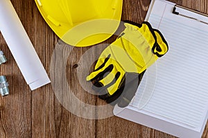 Architect or engineer working on blueprint architecture mode in office construction protective gloves on yellow safety helmet