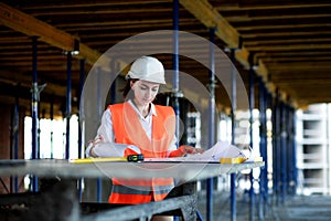 Architect or engineer working, browsing building project indoor of construction site with blueprint plan. Woman