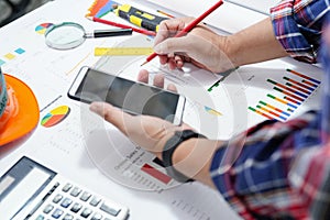 Architect or engineer working project accounting with graph, mobile phone and tools in office