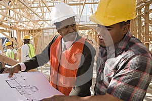 Architect And Foreman In Discussion Over Blueprint