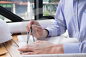 Architect hand holding drawing compass working on construction p