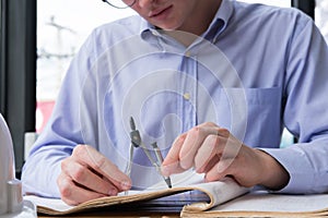 Architect hand holding drawing compass working on construction p