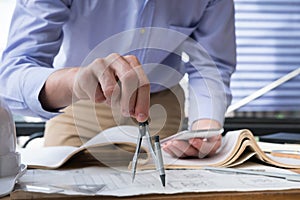 Architect hand holding drawing compass working on construction p
