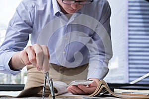 Architect hand holding drawing compass working on construction p