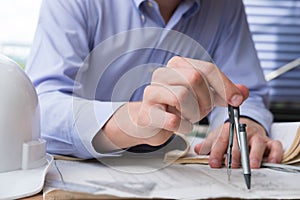 Architect hand holding drawing compass working on construction p