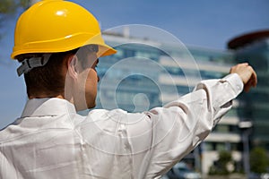 Architect in hardhat pointing at construction site