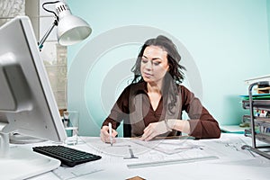 Architect at her working desk with blueprints in front