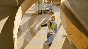 Architect holding his plans looks up at ceiling of CLT house under construction.