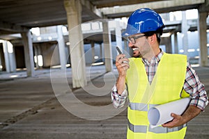 Architect holding rolled up blueprints at construction site