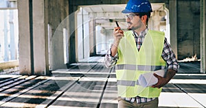 Architect holding rolled up blueprints at construction site