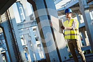 Architect holding rolled up blueprints at construction site