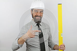 Architect man with beard wearing hardhat holding level tool pointing with finger