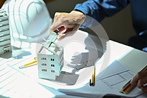 Architect man examining house model while working construction project in a creative office