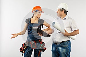 An architect man wearing a hard hat or helmet and co-worker builder woman reviewing blueprints
