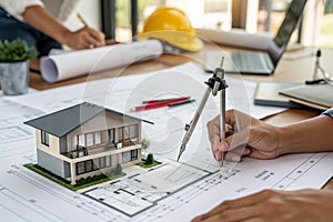 Architect measuring house blueprint with compass