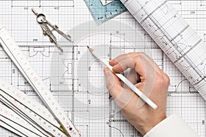 Architect pointing on architectural blueprint house building plan with pencil, ruler, compasses and square flatlay