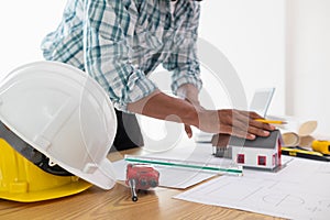 architect is preparing house model and construction plans on blueprints for construction engineering team to review before