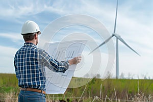 architect reviewing wind turbine blueprints onsite photo