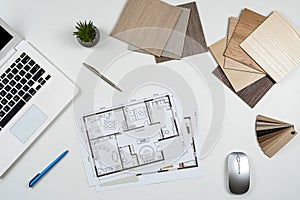 Architect's table with laptop, house plab blueprint and color wwoden sampler, other work tools