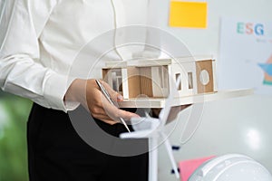 Sustainable Building Model Presentation. Professional holding eco-friendly design model in meeting.