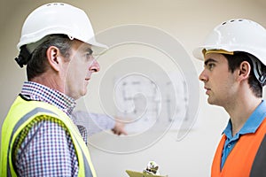 Architect On Site Discussing Plans With Builder