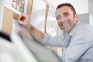 architect smiling and putting blueprint on office board photo