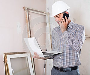 architect talking on the mobile phone with laptop in the hand