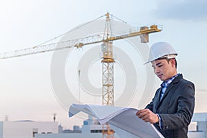 The architect wear white safety helmet and verify the blueprint
