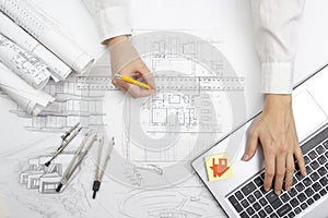 Architect working on blueprint. Architects workplace - architectural project, blueprints, ruler, calculator, laptop and