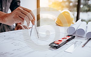 Architect working on blueprint in workplace and drawing compass.