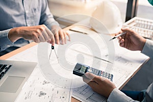 Architect working on blueprint in workplace with partnership and drawing compass